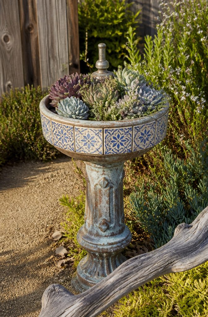 Repurposed drinking fountain with succulents planted among original art tiles