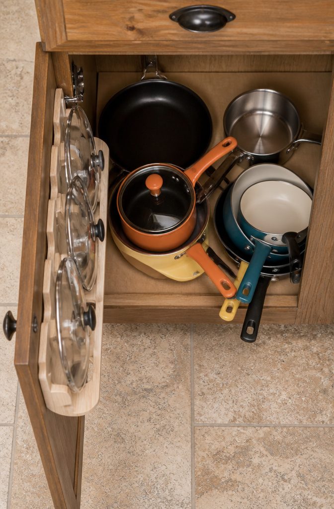 How to Organize Pots and Pans: 12 Ideas for Any Kitchen in 2026 7 Pull-out rack organizing lids vertically inside a kitchen cabinet.