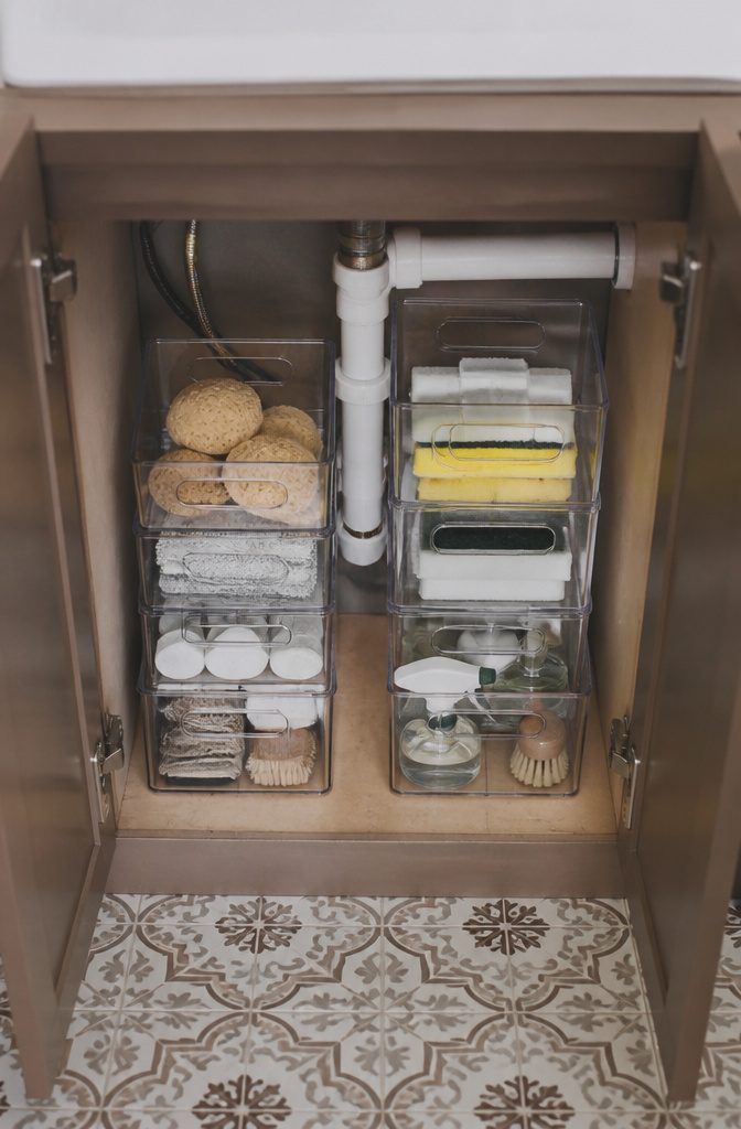 Under Sink Cabinet Organization Ideas for Kitchens and Bathrooms 3 Three clear acrylic stackable bins holding sponges and cleaning pads.